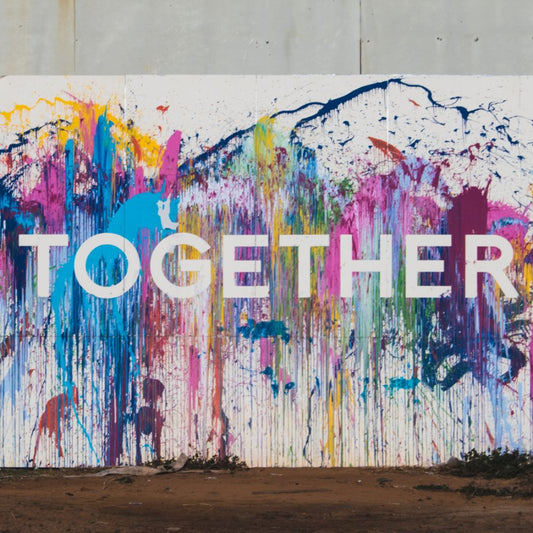 A wall covered in different paints. dripping down with the word, together, going right across.