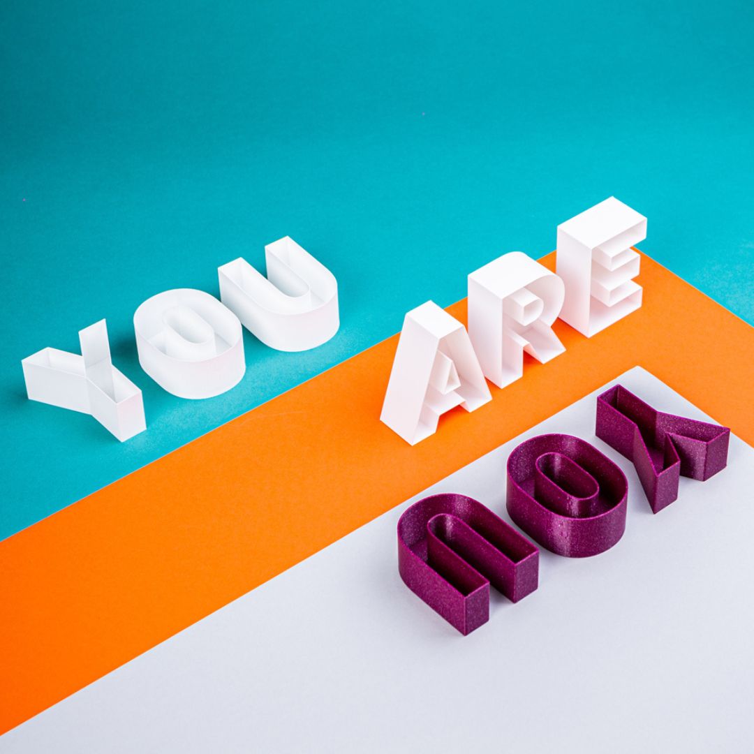 Three blocks of words on coloured paper of blue, orange and white also in blocks. The three words are you are you. The blocks are carefully placed on the coloured paper.